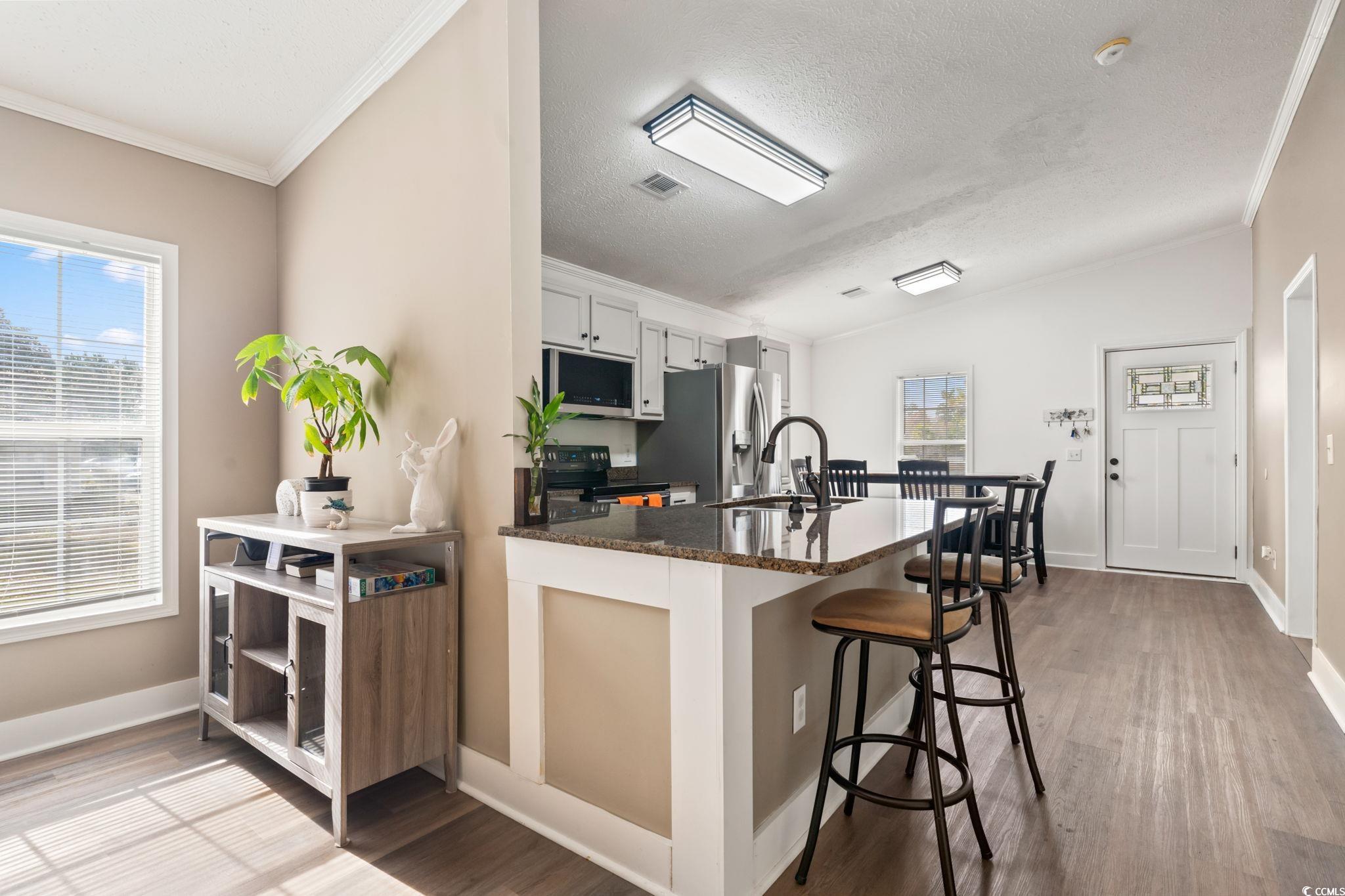 2977 Silverleaf Circle Loris, SC 29569 - Photo 11 of 36 Kitchen with a breakfast bar, dark stone countertops, a peninsula, dark wood-style floors, and ornamental molding
