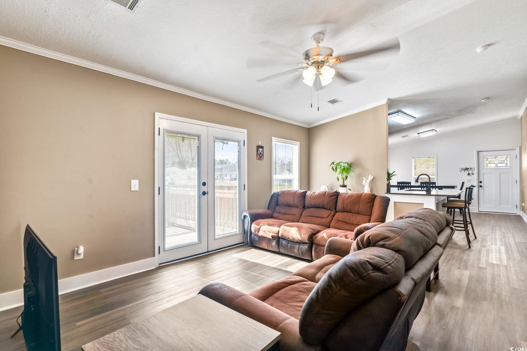 2977 Silverleaf Circle Loris, SC 29569 - Photo 14 of 36 Living room with plenty of natural light, wood finished floors, a textured ceiling, ornamental molding, and ceiling fan