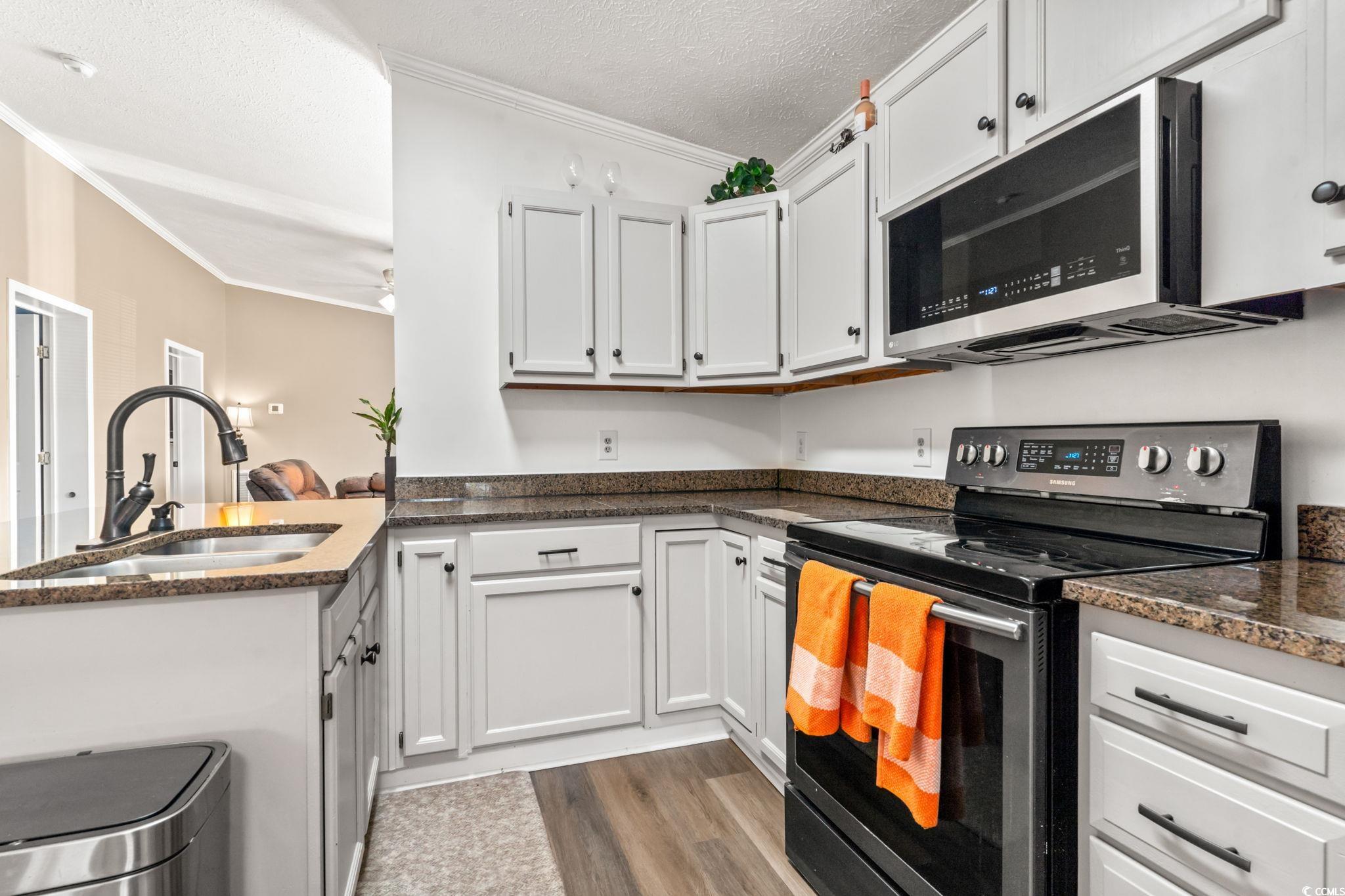 2977 Silverleaf Circle Loris, SC 29569 - Photo 5 of 36 Kitchen featuring stainless steel appliances, ornamental molding, white cabinets, a textured ceiling, and a peninsula