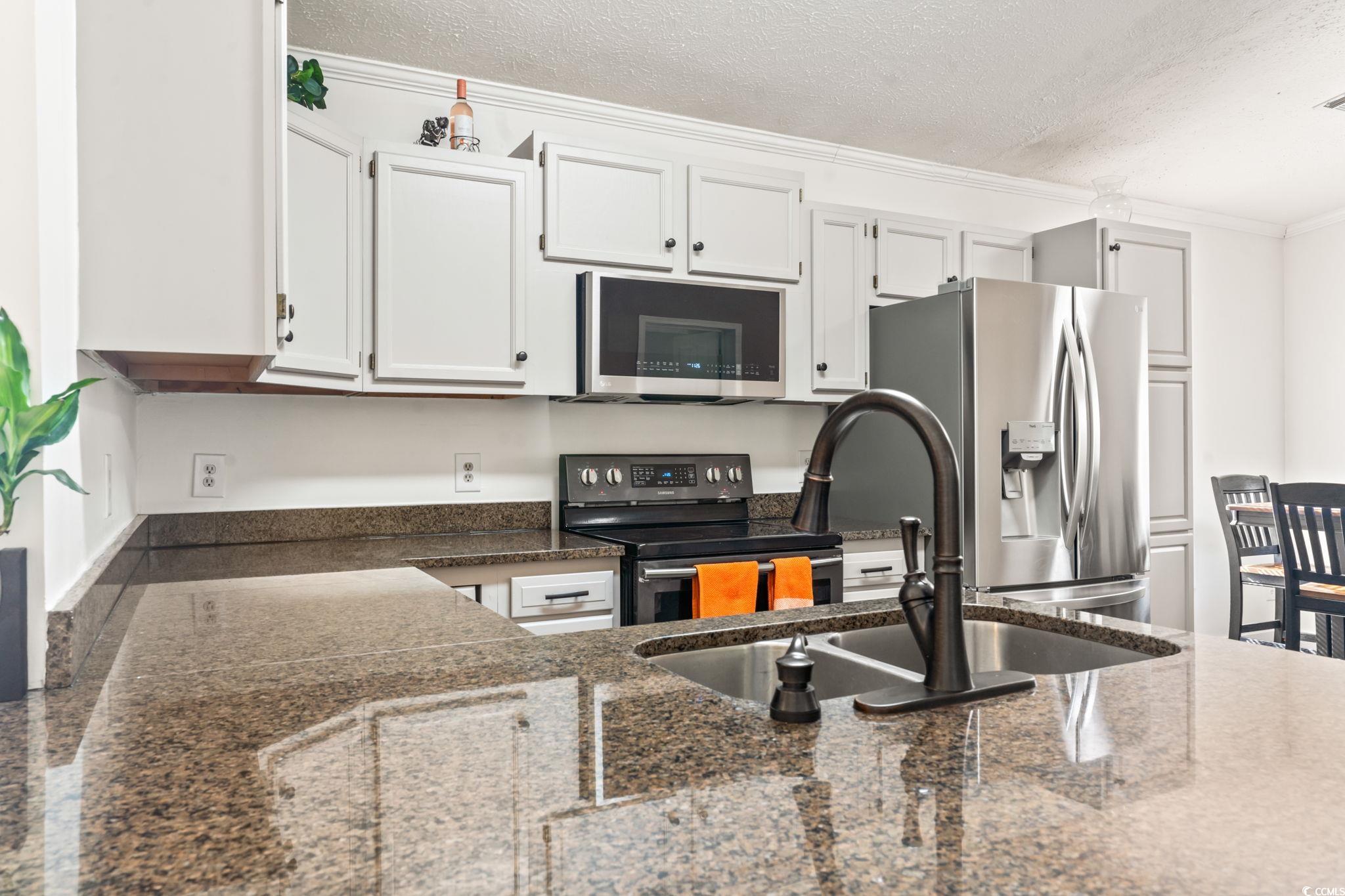 2977 Silverleaf Circle Loris, SC 29569 - Photo 6 of 36 Kitchen featuring stainless steel appliances, white cabinetry, a textured ceiling, crown molding, and dark stone counters