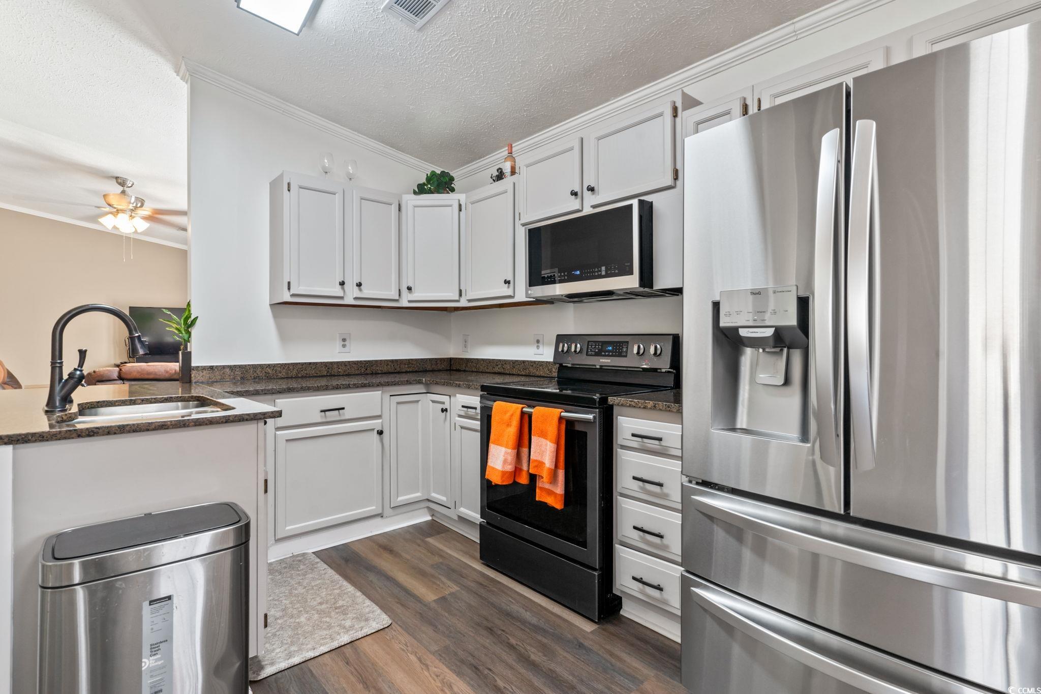 2977 Silverleaf Circle Loris, SC 29569 - Photo 8 of 36 Kitchen featuring stainless steel appliances, crown molding, white cabinetry, a textured ceiling, and dark wood-type flooring