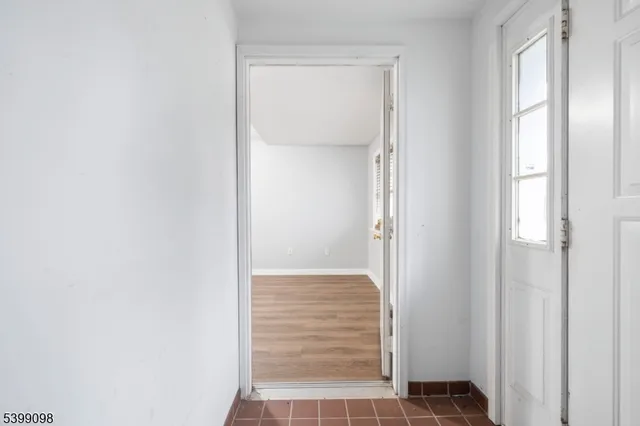 a view of an empty room with wooden floor and stairs