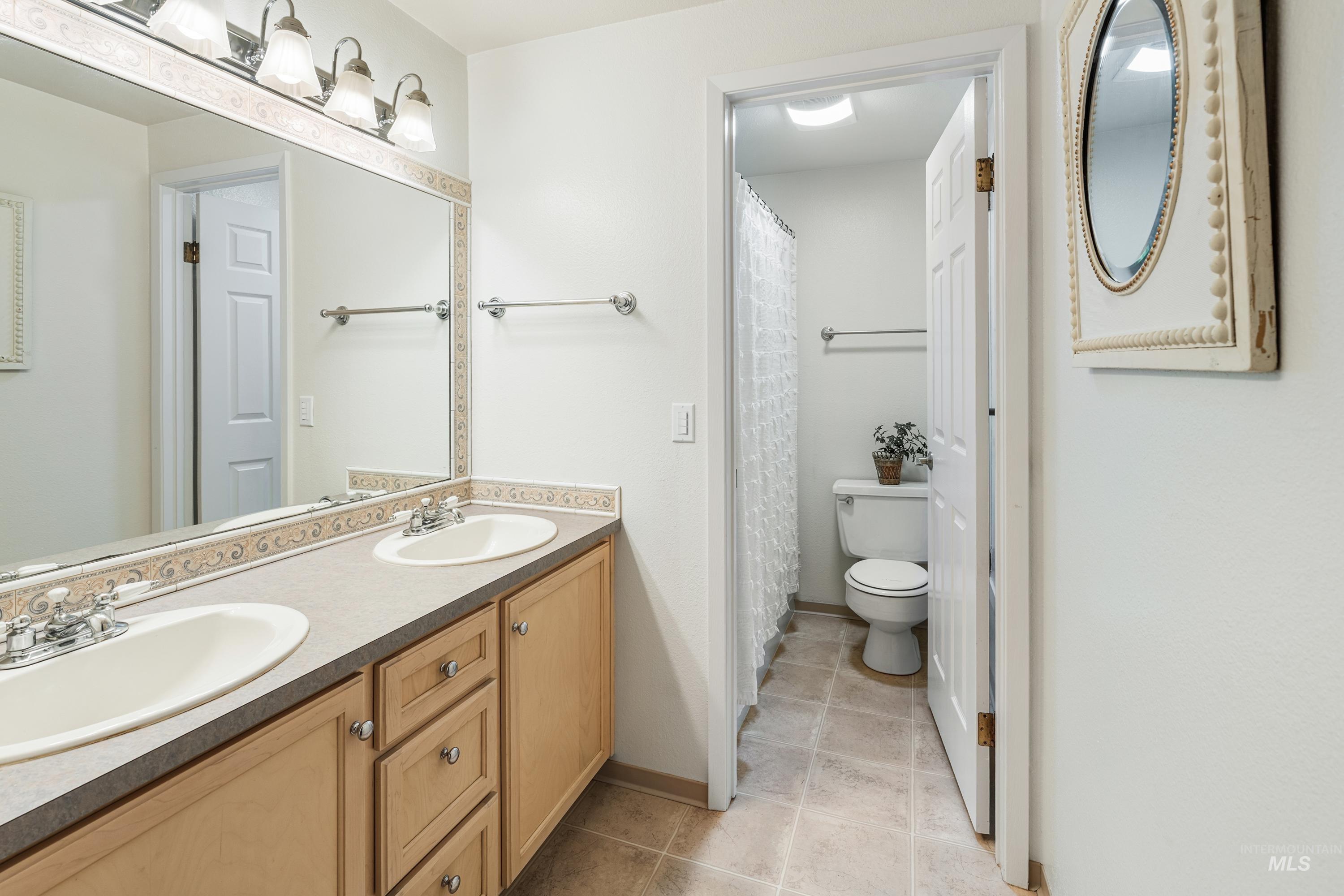 2963 Mayfair Ridge Lewiston, ID 83501 - Photo 36 of 45 Double vanity with dual undermount sinks, wood-finish cabinetry, and a full-width mirror
