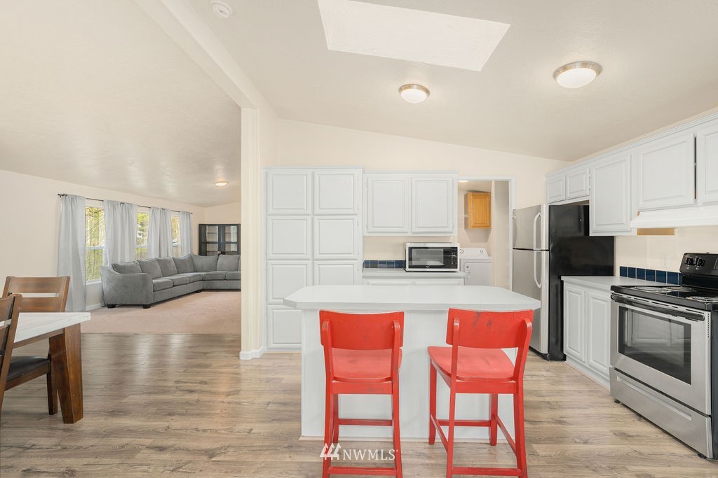 15400 Southeast 155th Place, Unit 7 Renton, WA 98058 - Photo 12 of 26 a kitchen with stainless steel appliances kitchen island granite countertop a dining table chairs and a refrigerator