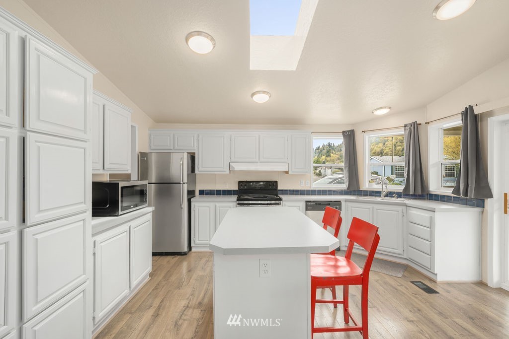 15400 Southeast 155th Place, Unit 7 Renton, WA 98058 - Photo 13 of 26 a kitchen with stainless steel appliances a microwave a stove a refrigerator a sink dishwasher and white cabinets with wooden floor