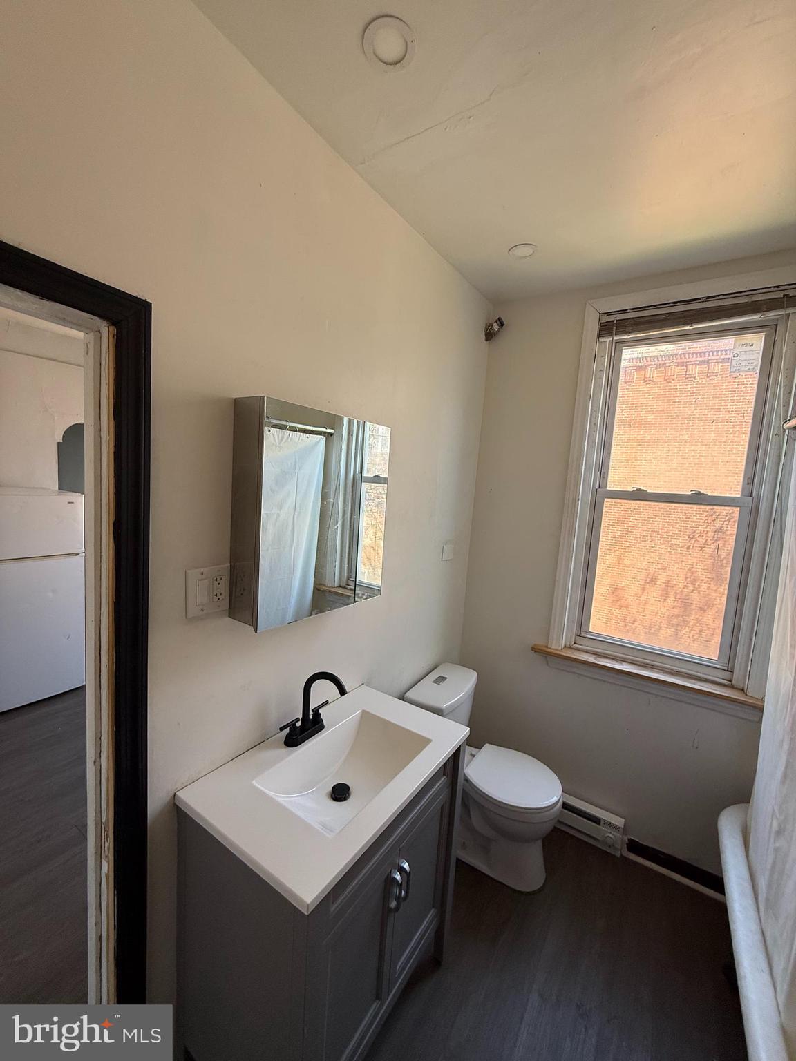 5336 Vine Street, Unit 2F Philadelphia, PA 19139 - Photo 6 of 7 a bathroom with a toilet sink and mirror
