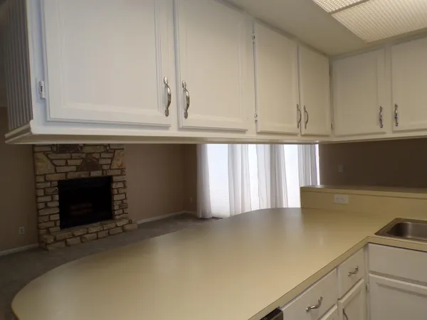 a view of kitchen with granite countertop white cabinets and a fireplace