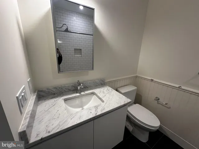 a bathroom with a granite countertop sink a toilet and a mirror