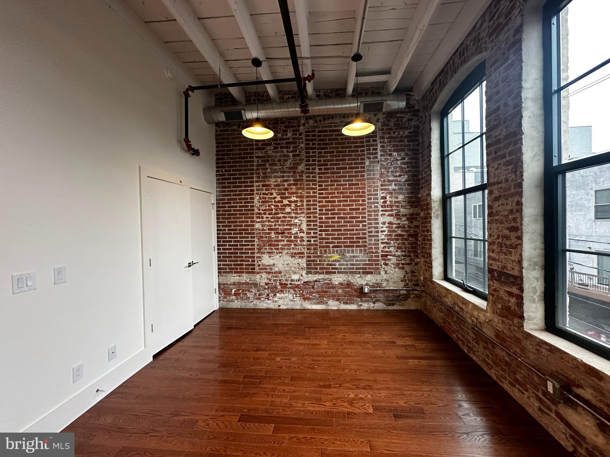 1801 North Howard Street, Unit 208 Philadelphia, PA 19122 - Photo 4 of 17 a view of an empty room with wooden floor and windows