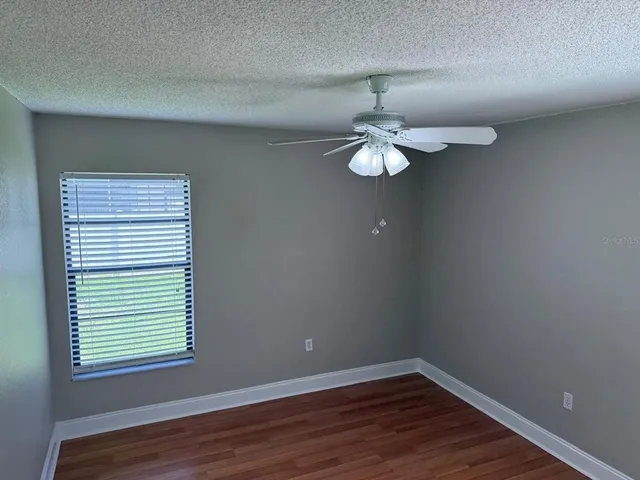 an empty room with wooden floor chandelier and windows