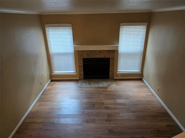 an empty room with wooden floor fireplace and windows