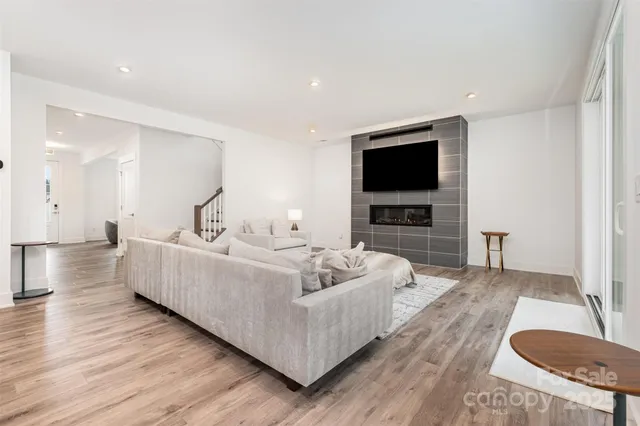 a living room with couches and kitchen view with wooden floor