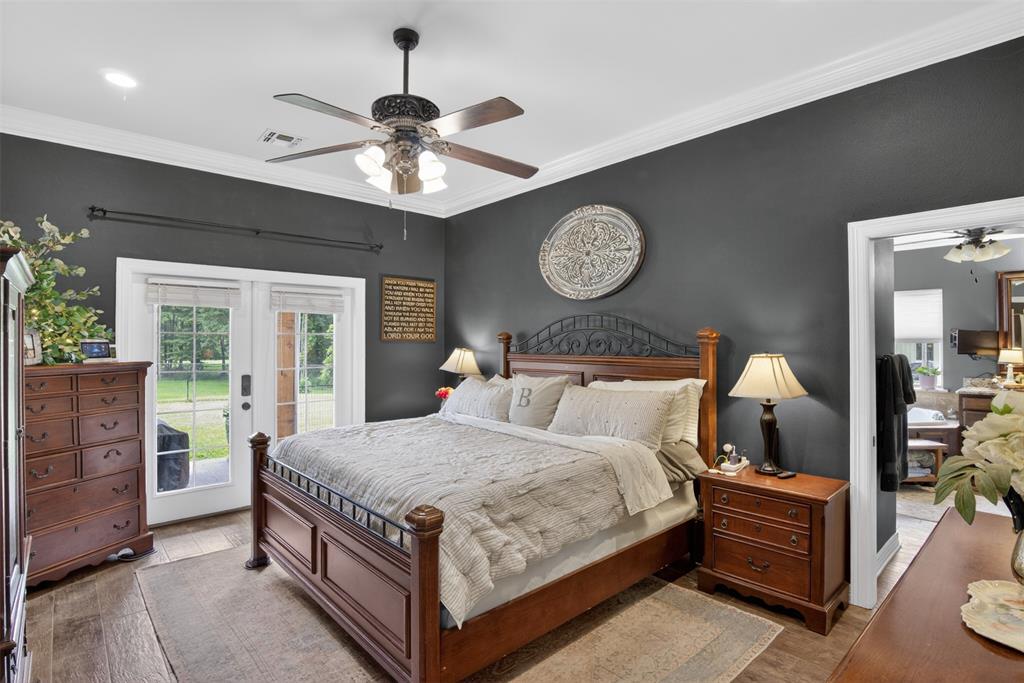 11868 Timber Ridge Drive Keithville, LA 71047 - Photo 14 of 37 Bedroom with dark-toned walls, wood-finish flooring, white crown molding, and a ceiling fan with integrated lighting