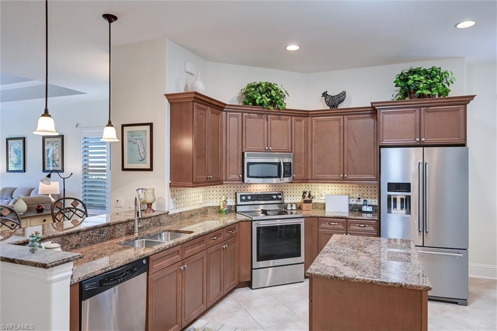 7587 Moorgate Point Way Naples, FL 34113 - Photo 24 of 50 Kitchen featuring wood cabinetry, stainless steel appliances, granite countertops, and tile flooring