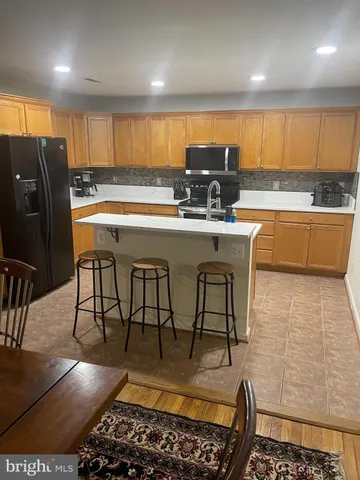 a kitchen with stainless steel appliances granite countertop a table chairs sink refrigerator and microwave