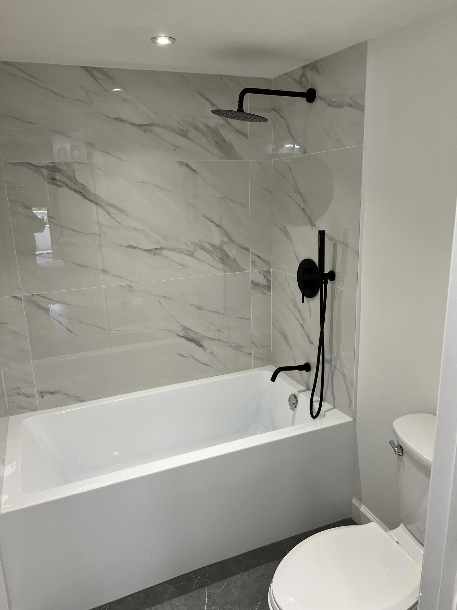 23200 Camino Del Mar, Unit 303 Boca Raton, FL 33433 - Photo 18 of 33 a white toilet and tub sitting next to a bathroom sink