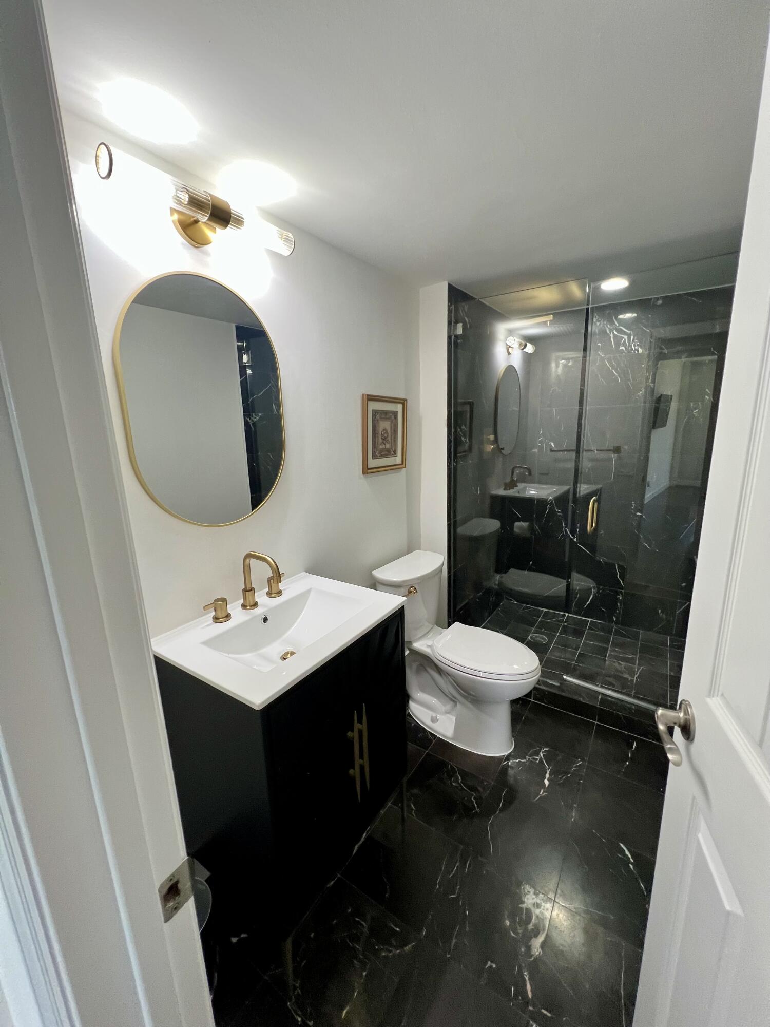 23200 Camino Del Mar, Unit 303 Boca Raton, FL 33433 - Photo 21 of 33 a bathroom with a toilet a sink and mirror