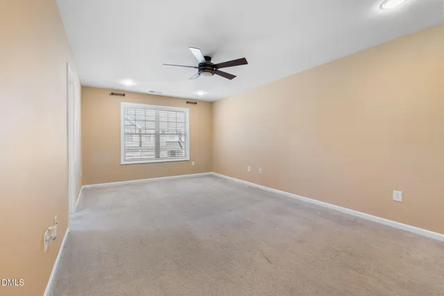 an empty room with windows and ceiling fan