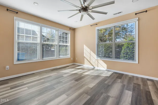 a view of an empty room with a window and wooden floor