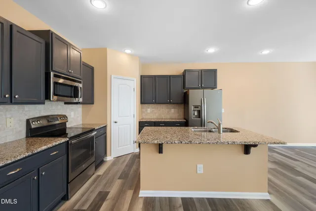 a kitchen with kitchen island granite countertop stainless steel appliances and wooden cabinets