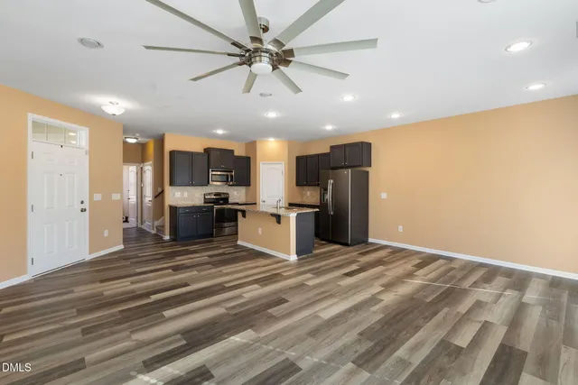 a view of kitchen with stainless steel appliances kitchen island granite countertop refrigerator stove microwave and cabinets