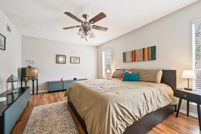 a spacious bedroom with a bed a chandelier and a dresser