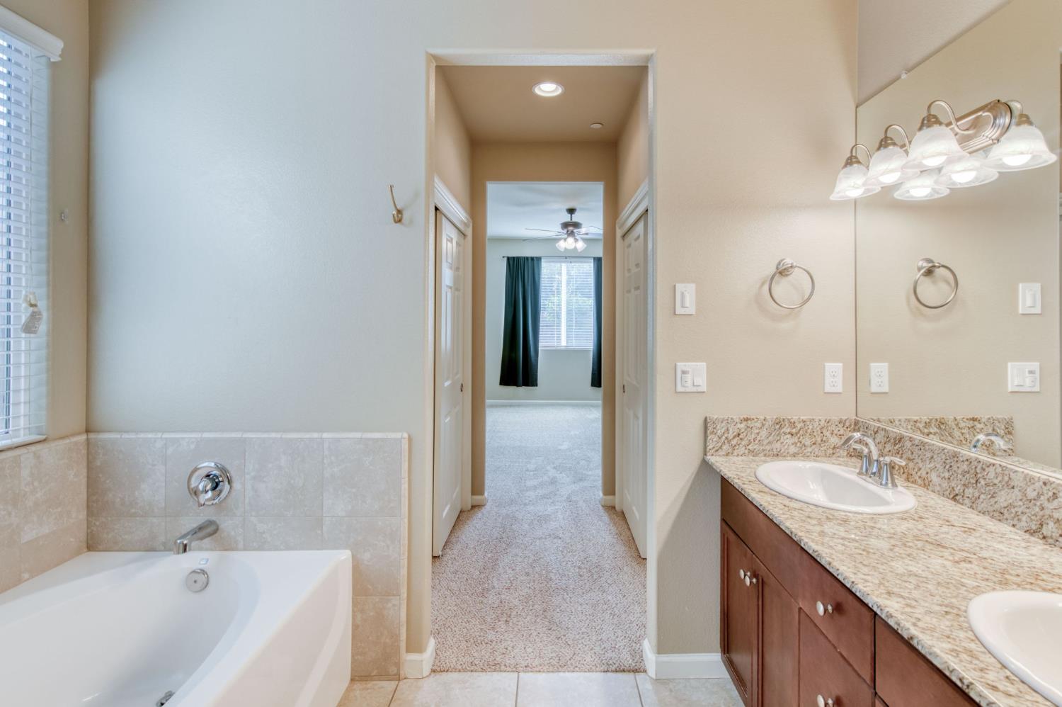 3460 Griffith Avenue Clovis, CA 93619 - Photo 5 of 28 a bathroom with a granite countertop sink a large mirror and bathtub