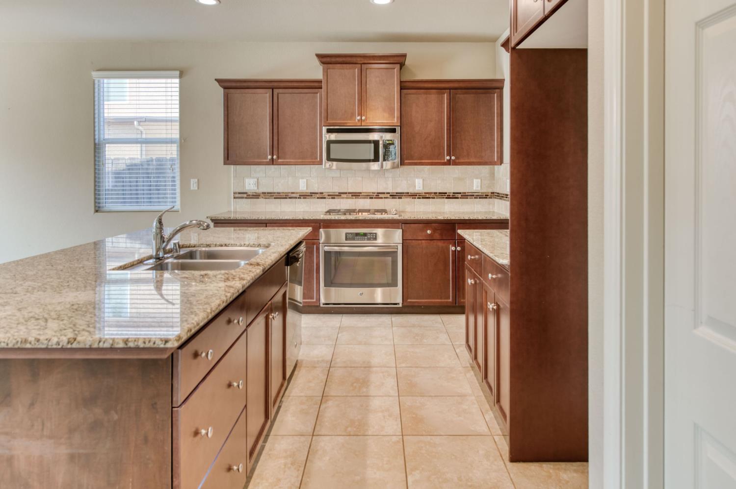 3460 Griffith Avenue Clovis, CA 93619 - Photo 9 of 28 a kitchen with kitchen island granite countertop a sink stove and cabinets