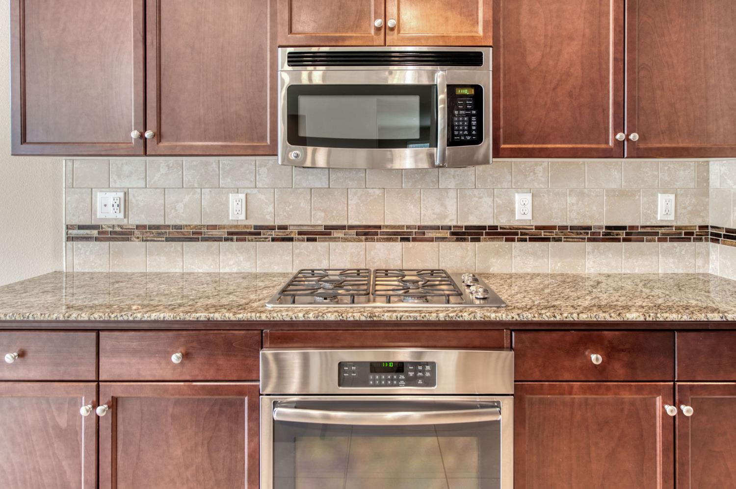 3460 Griffith Avenue Clovis, CA 93619 - Photo 10 of 28 a kitchen with granite countertop a stove top oven cabinetry and granite counter tops