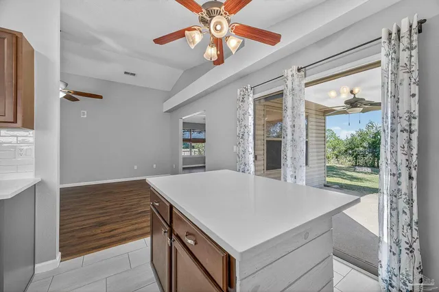 an empty room with wooden floor cabinet and windows