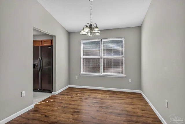a big room with wooden floor a ceiling fan and windows