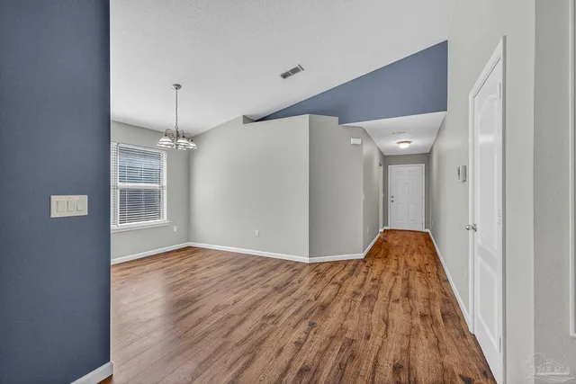 a view of a hallway with wooden floor and a refrigerator