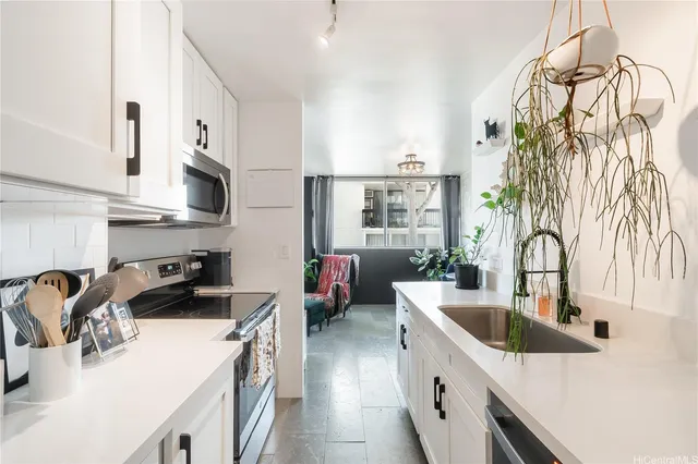 a kitchen with stainless steel appliances a sink a stove top oven a counter space and cabinets