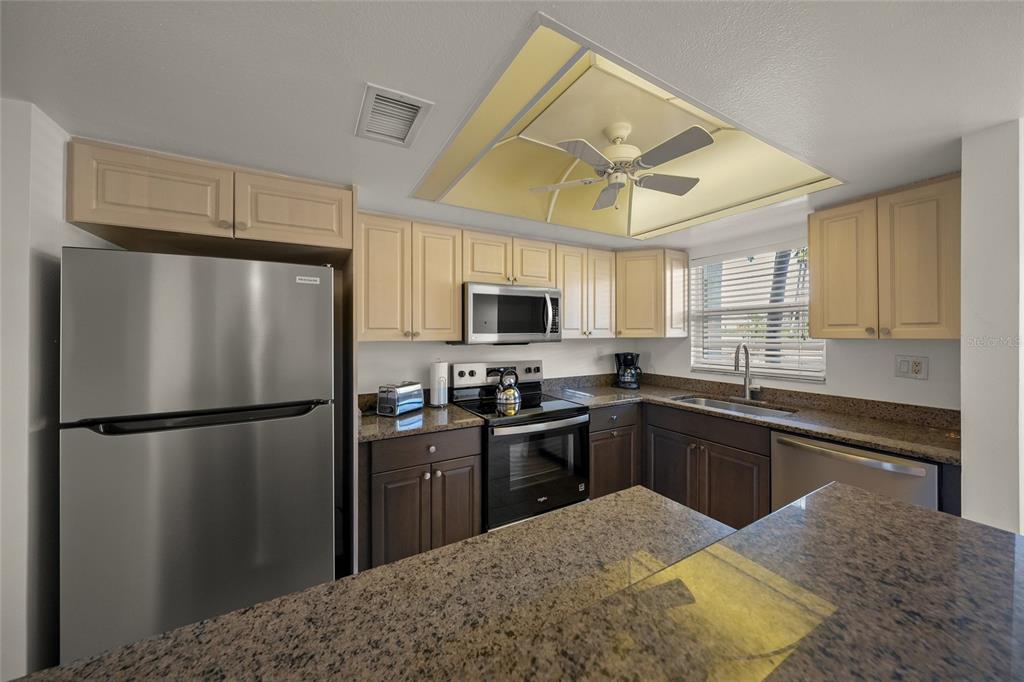 9200 Midnight Pass Road, Unit 17 Sarasota, FL 34242 - Photo 9 of 56 a kitchen with stainless steel appliances granite countertop a refrigerator a stove a sink dishwasher and a refrigerator with wooden floor