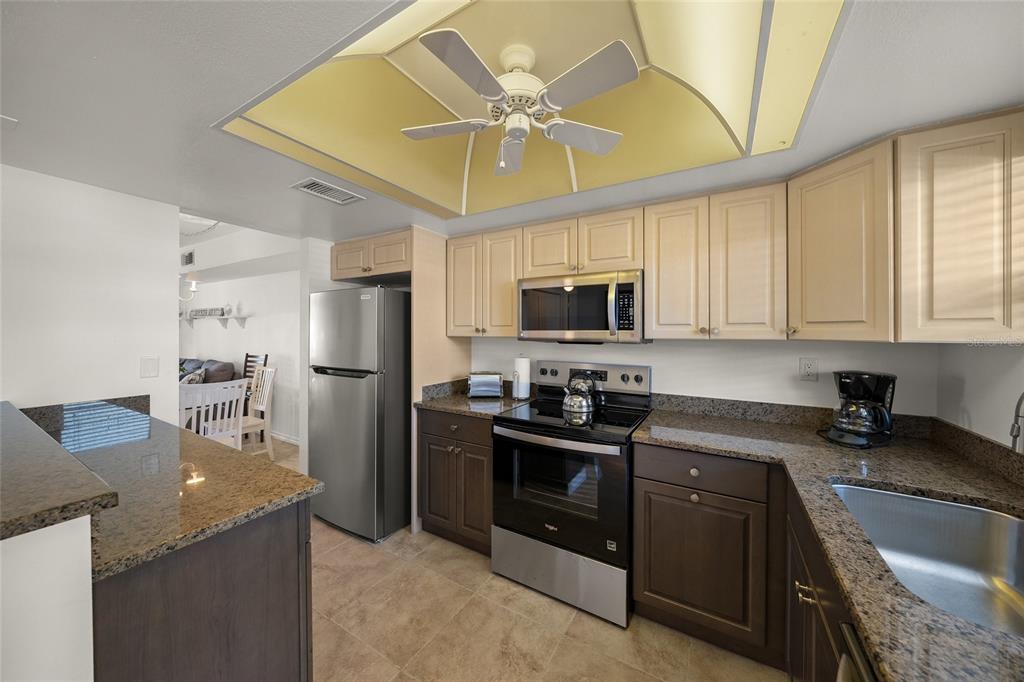9200 Midnight Pass Road, Unit 17 Sarasota, FL 34242 - Photo 10 of 56 a kitchen with stainless steel appliances granite countertop a sink a stove top oven a refrigerator with grey cabinets