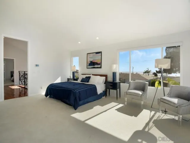a spacious bedroom with a bed a lamp on desk and a window