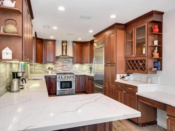 a kitchen with stainless steel appliances granite countertop a stove top oven a sink dishwasher a dining table and chairs with wooden floor