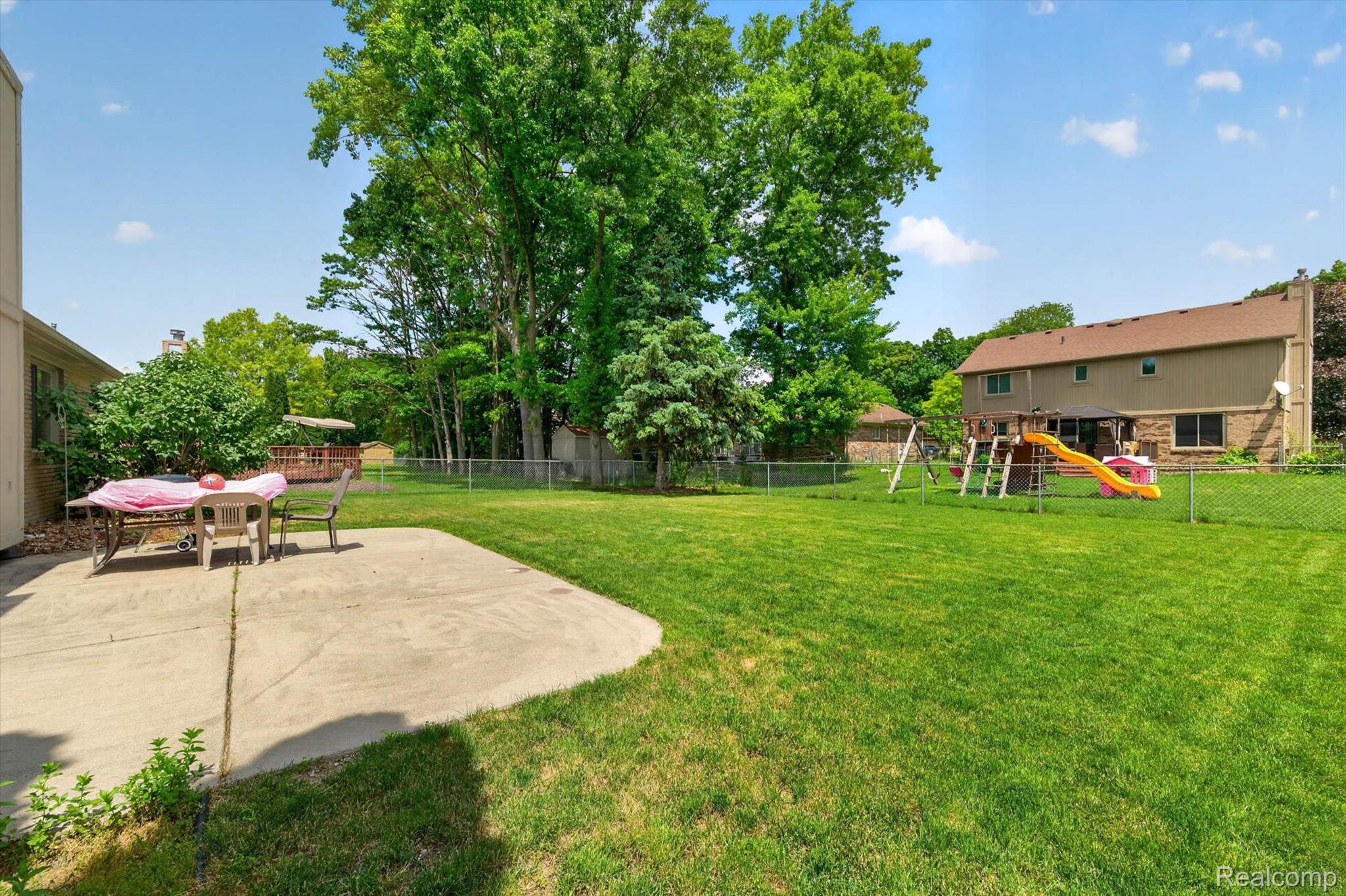 46362 Springhill Drive Utica, MI 48317 - Photo 40 of 59 Expansive green lawn with mature trees and a chain-link perimeter fence