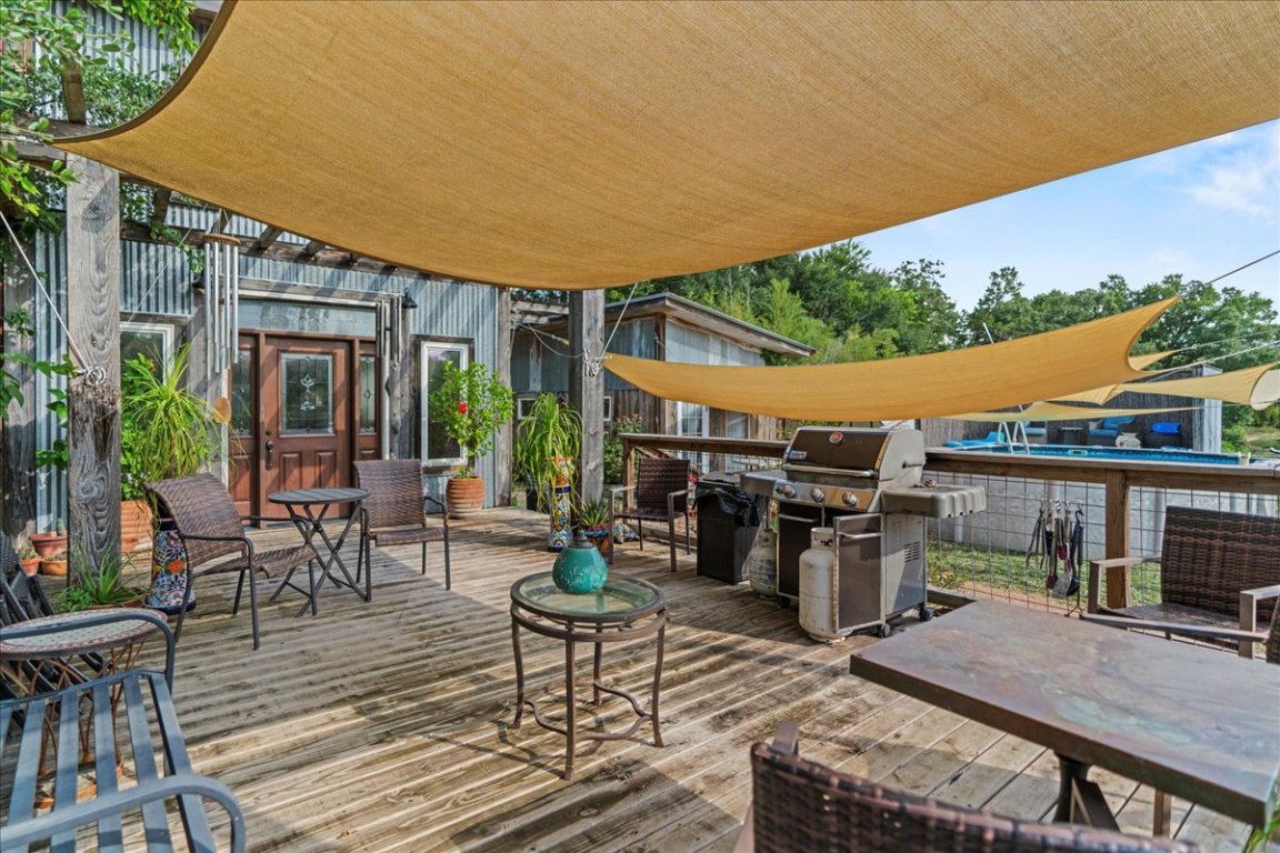 16933 B Ranch Road 12, Unit B Wimberley, TX 78676 - Photo 7 of 19 a view of a patio with table and chairs potted plants with wooden floor and fence