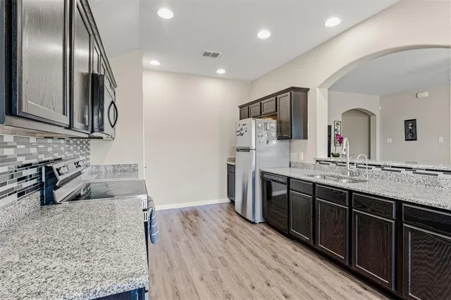 a kitchen with stainless steel appliances granite countertop a sink stove and refrigerator