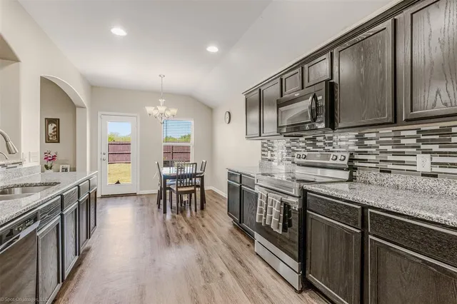 a kitchen with stainless steel appliances granite countertop wooden cabinets stove top oven and sink