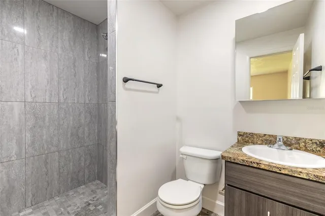 a bathroom with a granite countertop sink a toilet and shower
