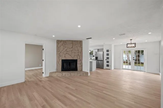 a view of an empty room with wooden floor and a fireplace