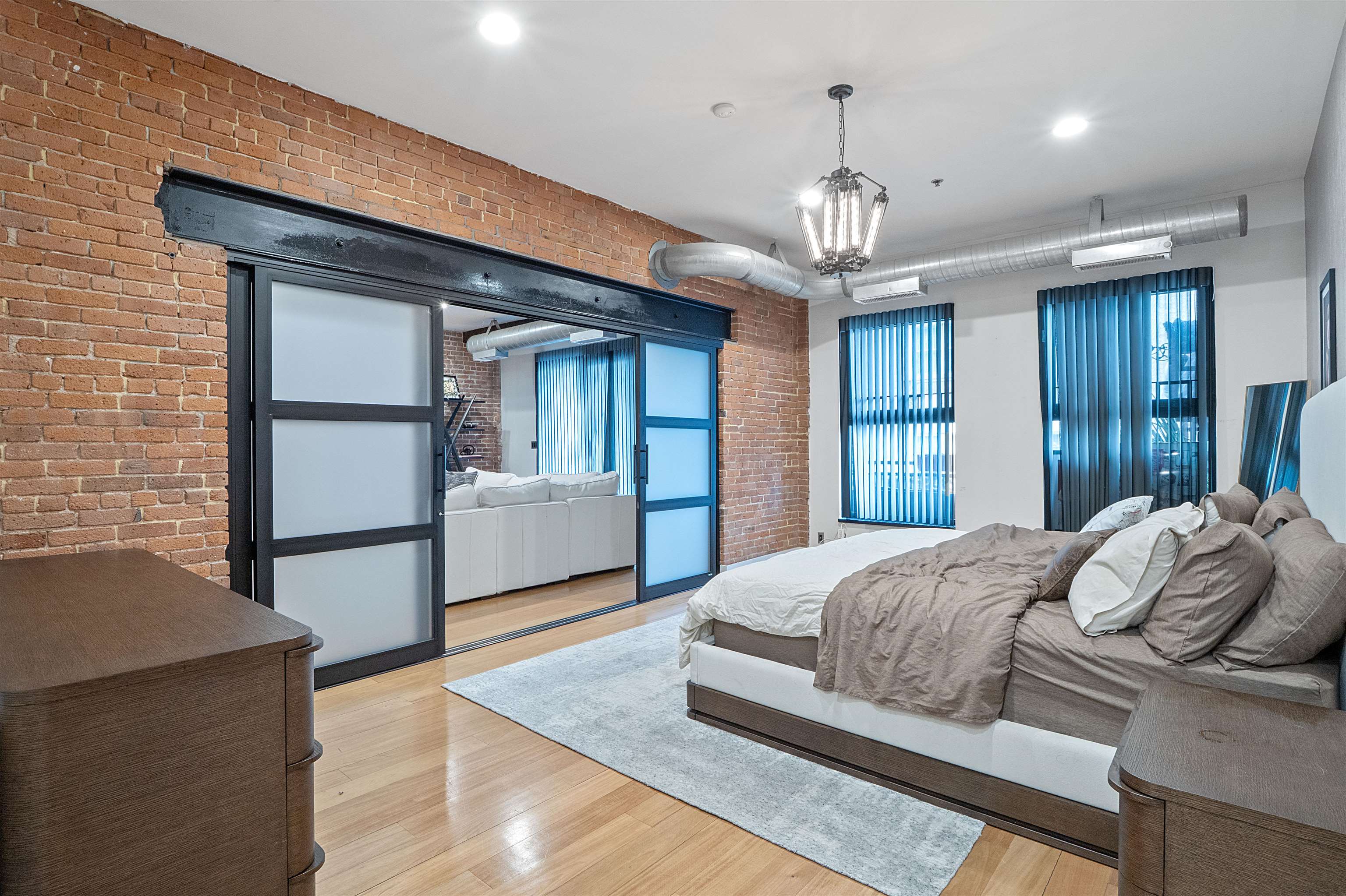 610 Clinton Street, Unit 2A Hoboken, NJ 07030 - Photo 27 of 33 a spacious bedroom with a bed a dresser and a chandelier