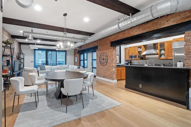 a dining hall with stainless steel appliances granite countertop a table chairs and a wooden floor