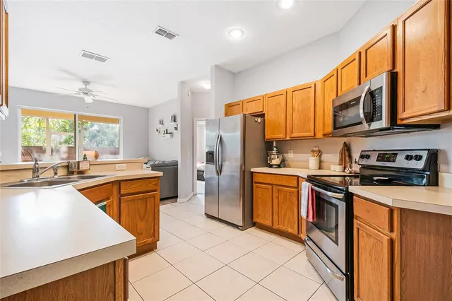 a kitchen with stainless steel appliances granite countertop a refrigerator a sink dishwasher a stove and white countertops with wooden floor