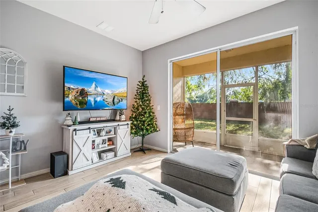a living room with furniture a flat screen tv and a floor to ceiling window