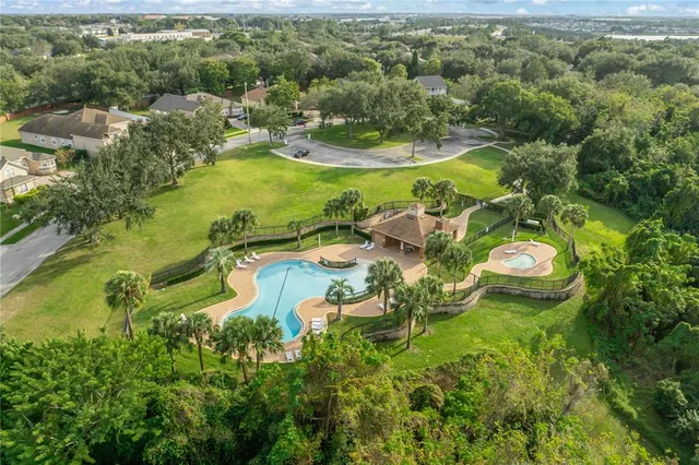 an aerial view of a house with outdoor space and trees all around