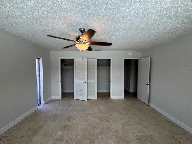 a view of an empty room with a chandelier fan