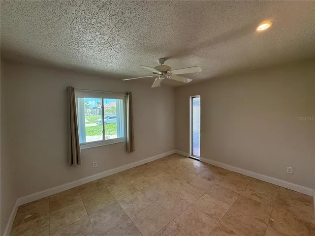 an empty room with a ceiling fan and window